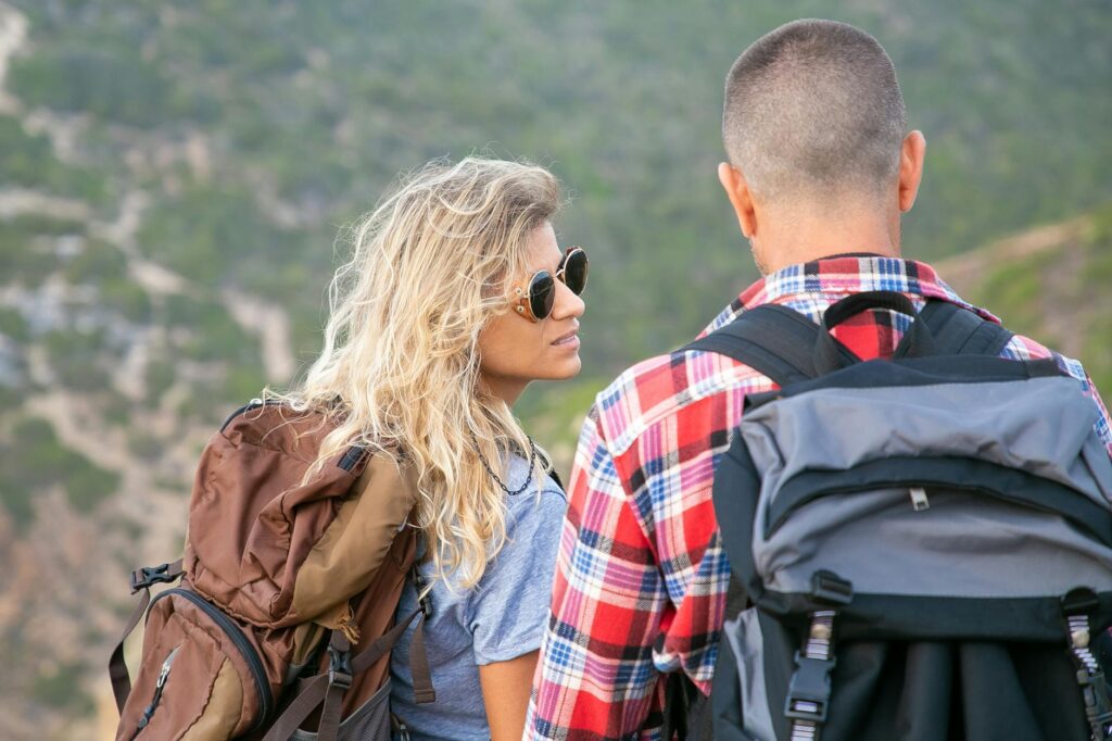 A young couple hiking in Portugal, enjoying the scenic outdoors with backpacks.