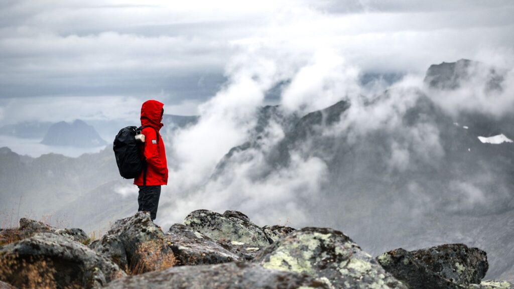 A woman stands on a mountain peak in Norway, embracing the misty and rugged landscape.