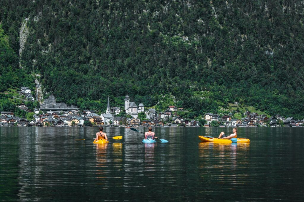 Three kayakers enjoying a day out on Lake Hallstatt with scenic village views in the background.