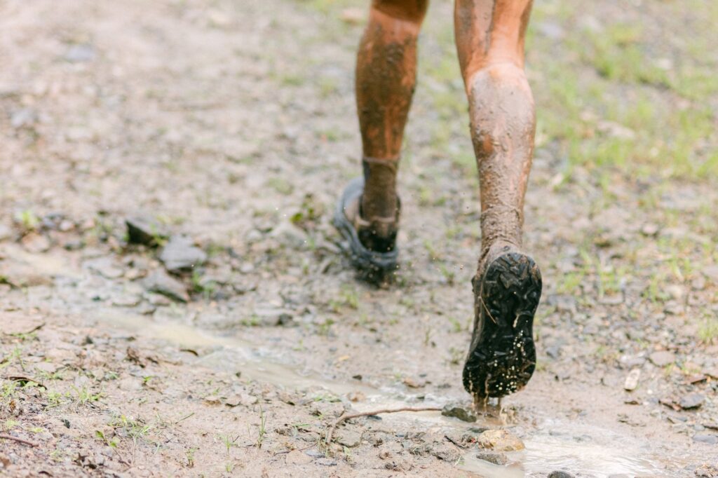 Close-up of muddy legs running on a wet trail, capturing the thrill of outdoor adventure.